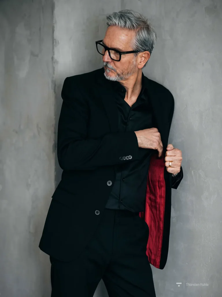 Eleganter Mann im schwarzen Anzug an Wand