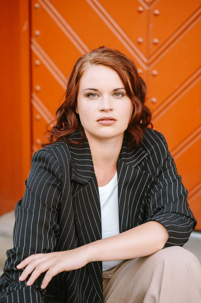 Woman in pinstripe blazer against orange door
