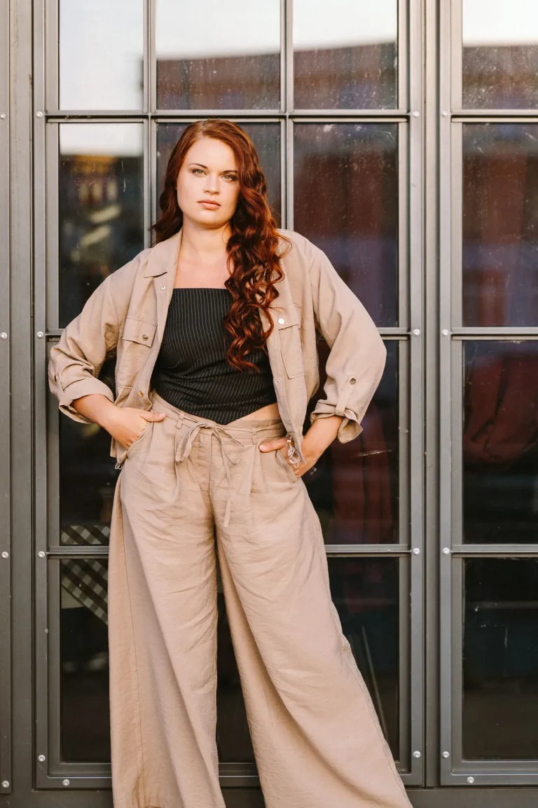 Woman in beige outfit standing by window