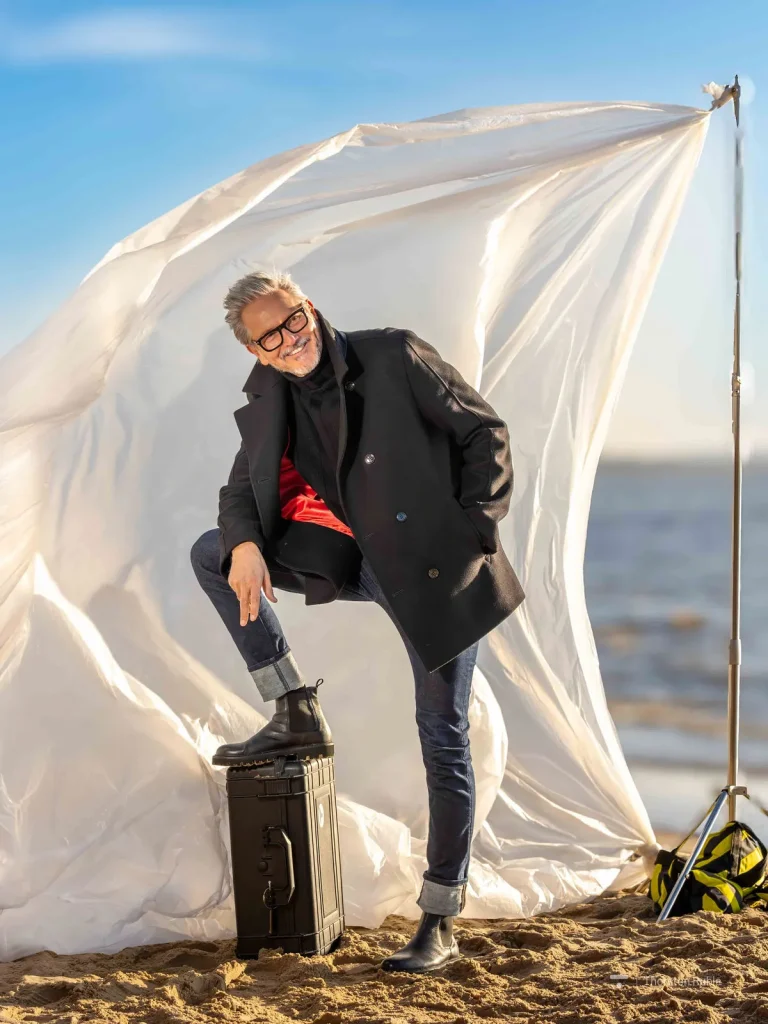 Stilvoller Mann am Strand vor wehender Plane
