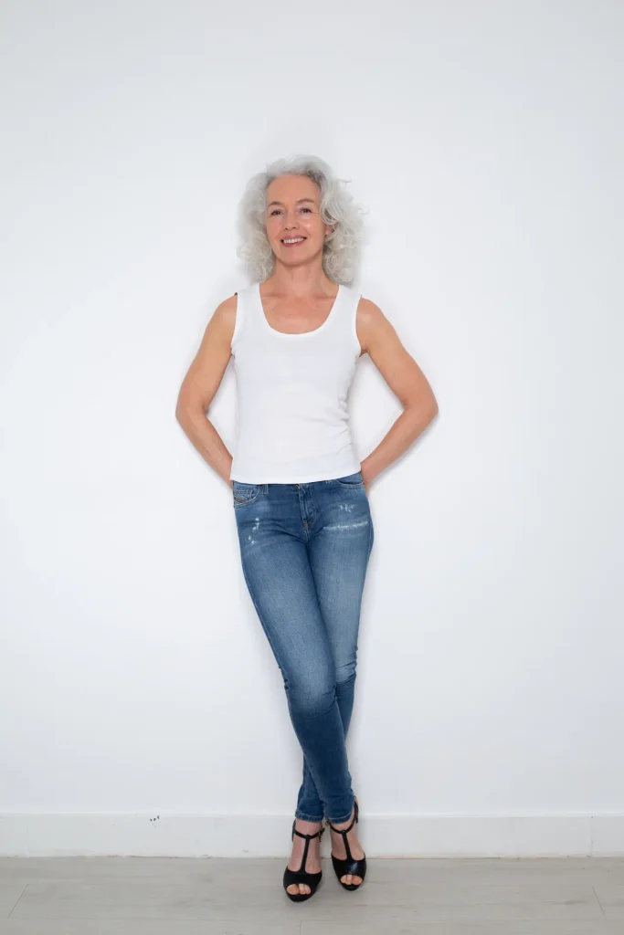 Lächelnde Frau mit grauen Locken in Jeans