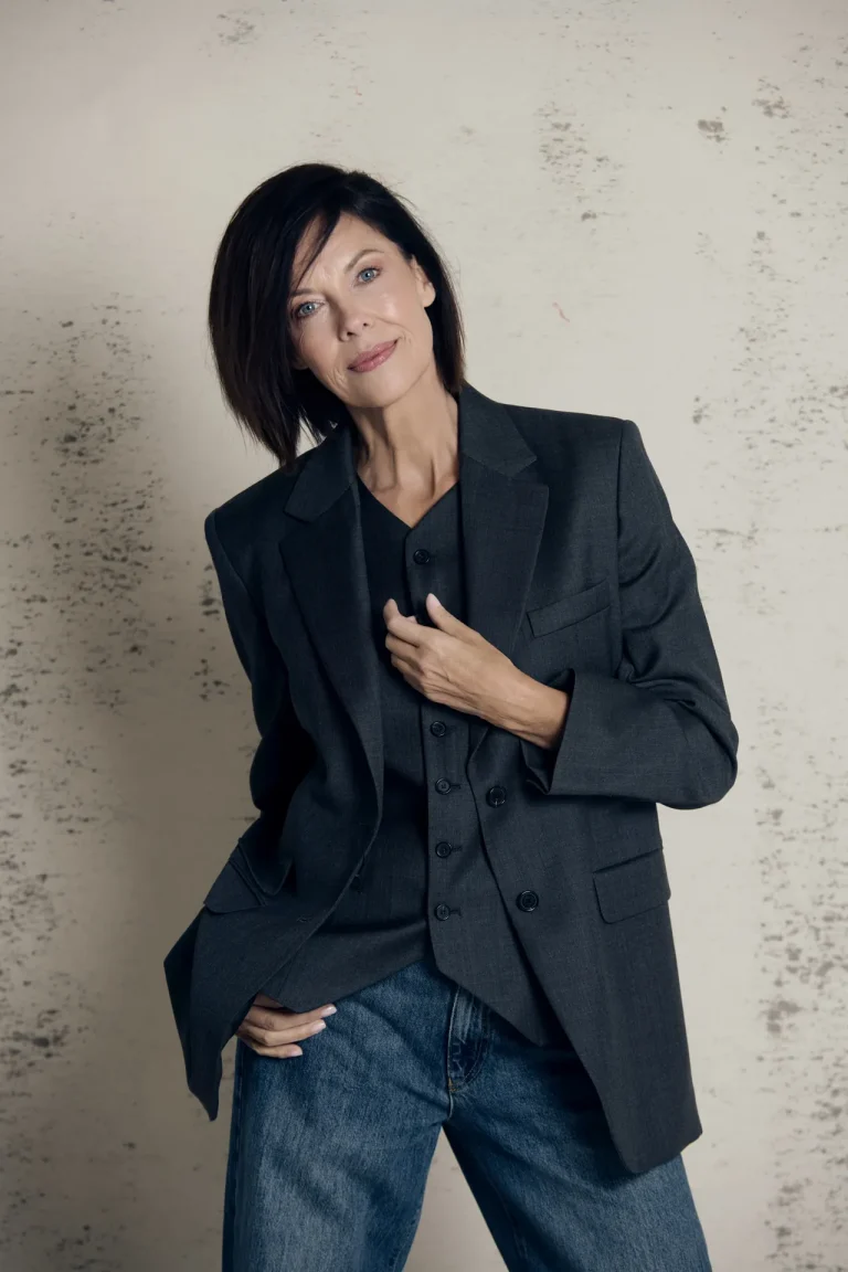 Frau im dunklen Blazer vor heller Wand