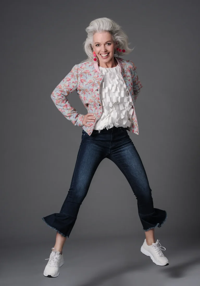 Lächelnde Frau in bunter Jacke und Jeans