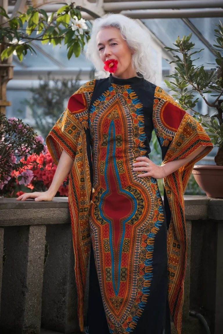 Frau im bunten Kaftan mit Blume im Mund