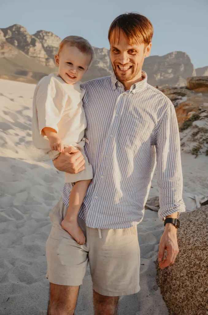 Vater mit Kleinkind am Strand bei Sonnenuntergang