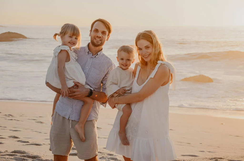 Familie mit zwei Kindern am Strand bei Sonnenuntergang